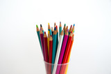 Colored wooden pencils for drawing in a glass stand on a white background. Children's multi-colored pencils for drawing.