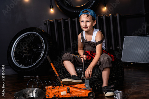 a child in a car repair shop among the wheels and car parts photo
