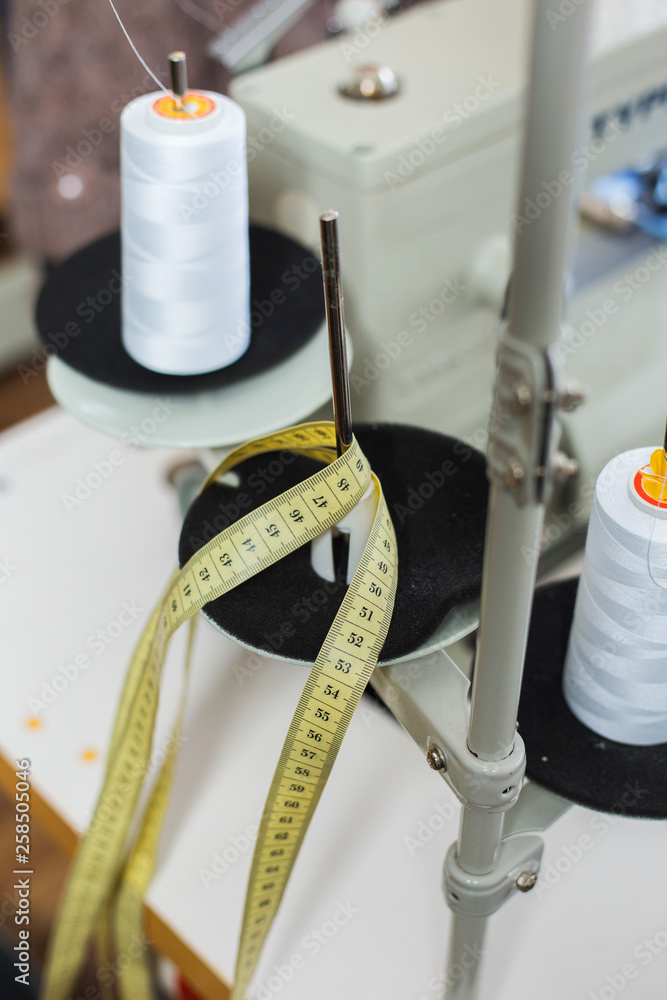 Φωτογραφία Closeup view of details of sewing machine and yellow measuring tape at garment factory