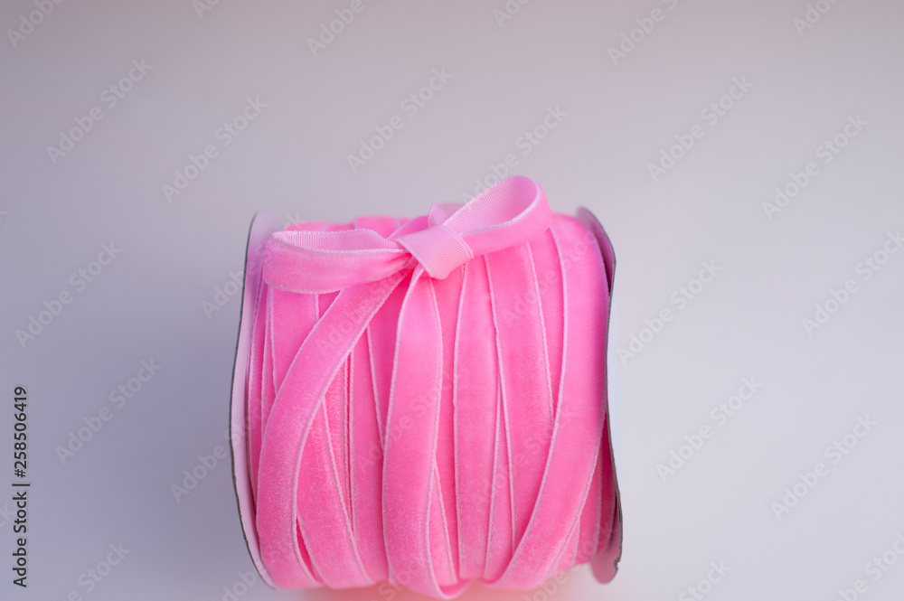 a roll of velvet pink ribbon for floristics and gift wrapping with a cute bow on the side a roll of velvet pink ribbon for floristics and gift wrapping with a cute bow on the side