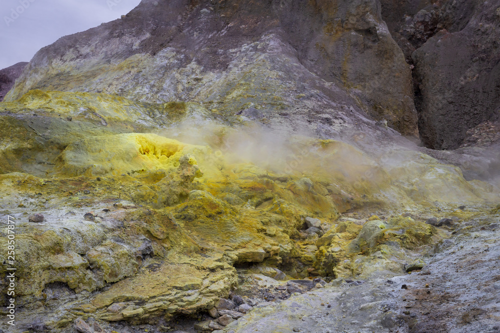 Landscape view of sulphur fumaroles, steam vents, sulfataras and hot mud springs on edge of crater at White Island, an active volcano in the Bay of Plenty, New Zealand. Landscape view of sulphur fumaroles, steam vents, sulfataras and hot mud springs on edge of crater at White Island, an active volcano in the Bay of Plenty, New Zealand.