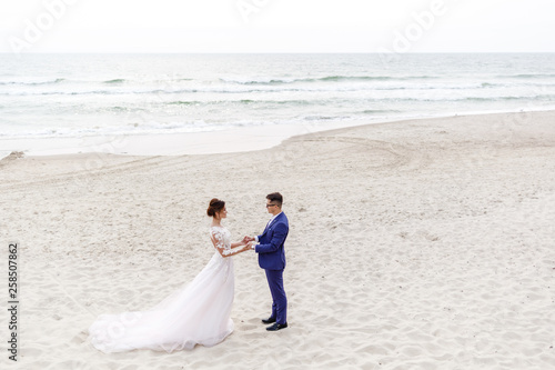 newlyweds walking along the sea beach at the wedding. The groom hugs the bride