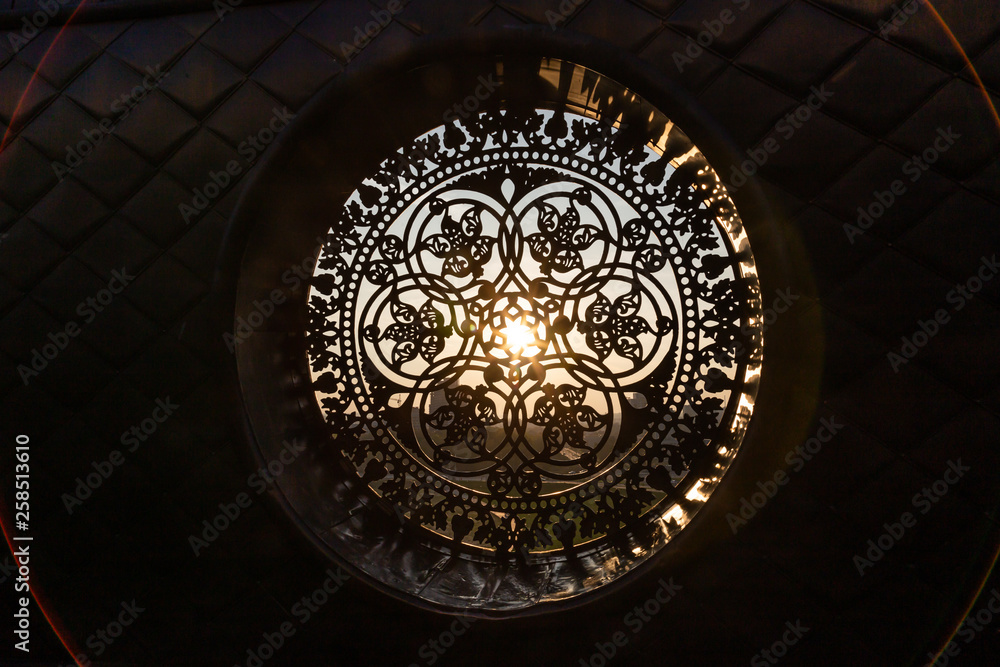 Fototapeta premium The sun's rays make their way through the cast-iron forged decorative lattice
