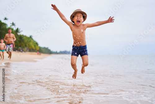 A child in a hat is jumping on the ocean - Asian boy in a hat, blurred background