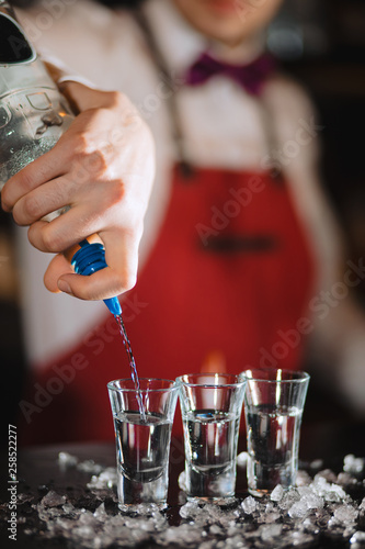 American bartender completing an order, focus on transparent short glasses standing on shaved or crushed ice. Night Life, alcohol drinks, luxury night club. photo