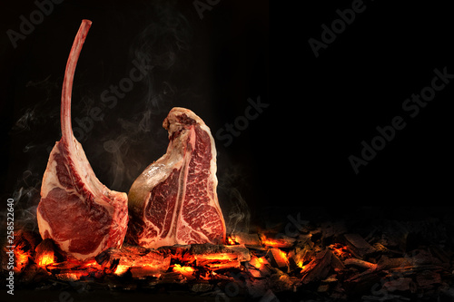 Whole T-Bone steak cooking on embers. Black background.