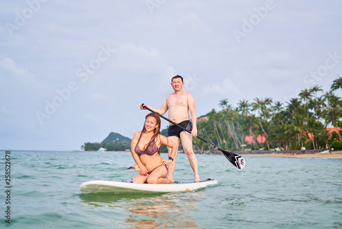 The girl and the guy ride on the sup board and laugh © Роман Ахметов