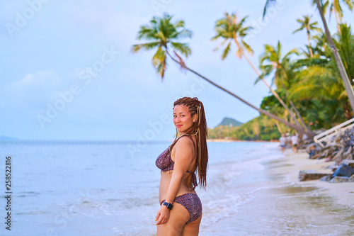 Asian girl stands on the beach - an afro pigtails near a tanned girl