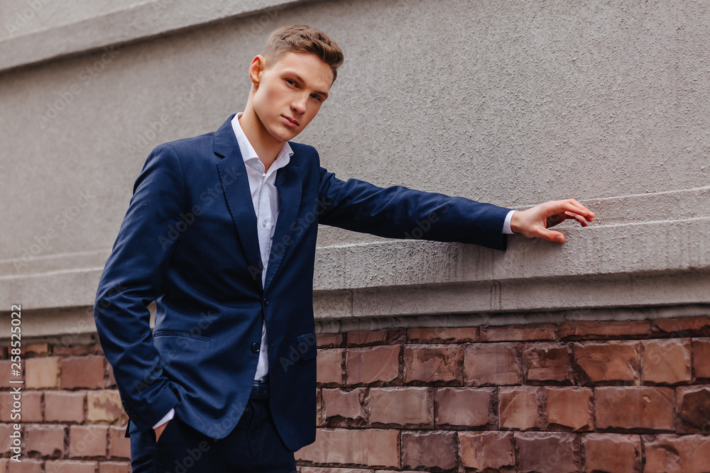 young stylish guy with a monumental face walks in a cool city near the wooden and stone walls young stylish guy with a monumental face walks in a cool city near the wooden and stone walls