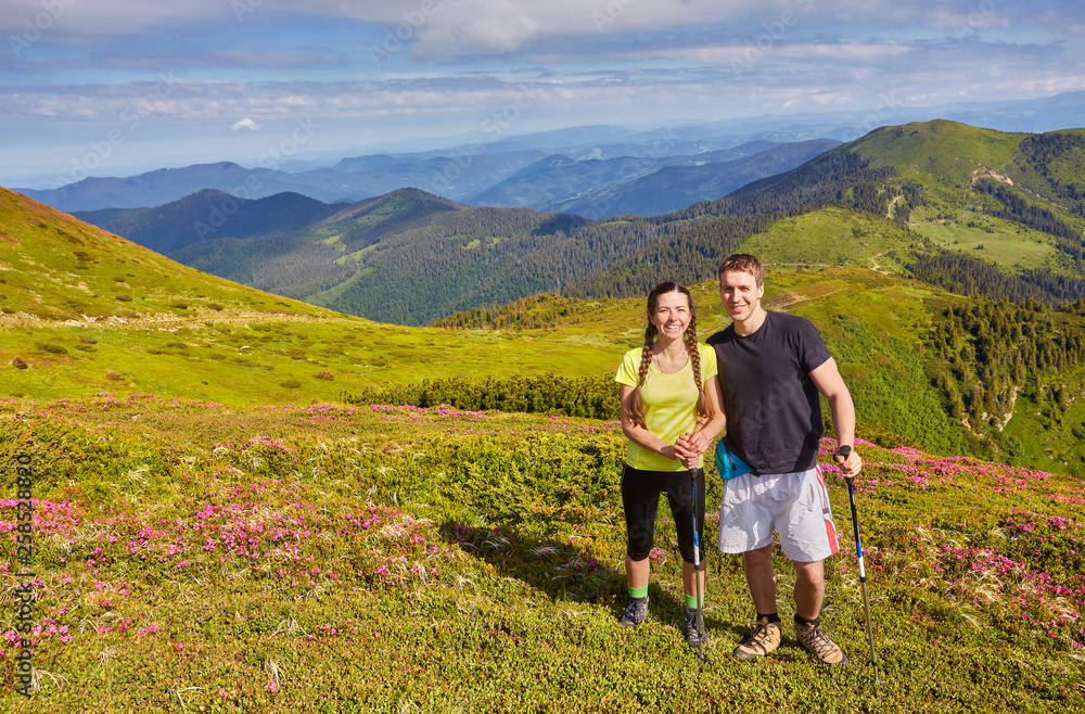 Man and woman standing and hugging on the top of the mountain, summer hike