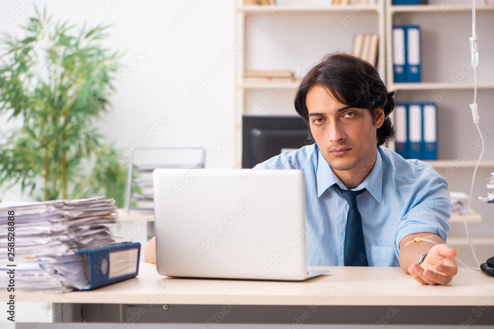 Young male employee in blood transfusion concept Young male employee in blood transfusion concept