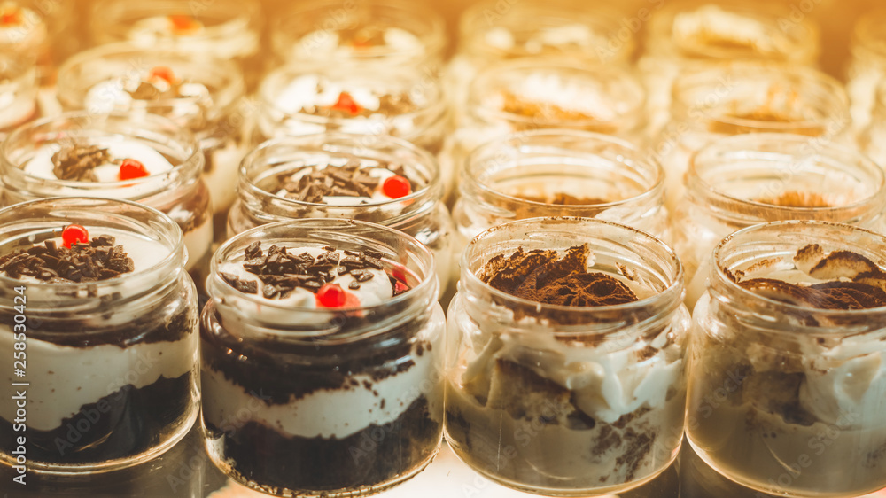 Fototapeta premium Many delicious desserts in a jar on the window of a cozy cafe. Tasty sweets
