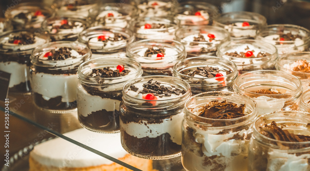 Many delicious desserts in a jar on the window of a cozy cafe. Tasty sweets
