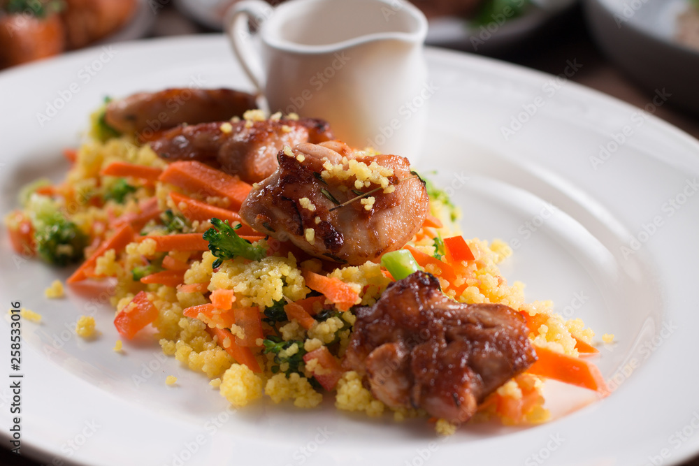 Grilled chicken fillet with vegetables and couscous on wooden table Grilled chicken fillet with vegetables and couscous on wooden table