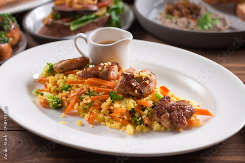 Grilled chicken fillet with vegetables and couscous on wooden table