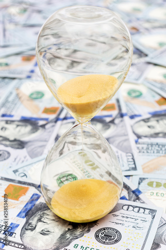 Hourglass on background of dollar bills.