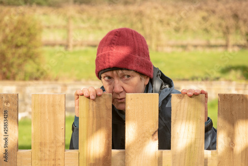 Mature woman hiding behind fence 
