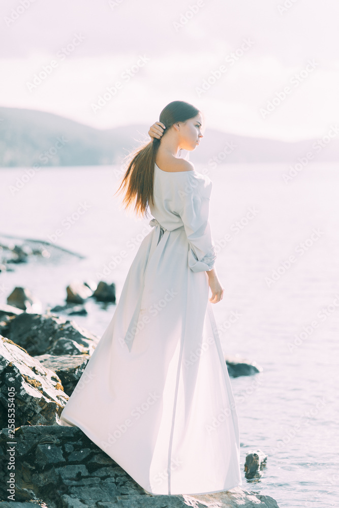Girl in boudoir dress on the lake, standing and smiling. Unity with nature, morning bride in Russia. Beautiful eyes and model appearance Girl in boudoir dress on the lake, standing and smiling. Unity with nature, morning bride in Russia. Beautiful eyes and model appearance