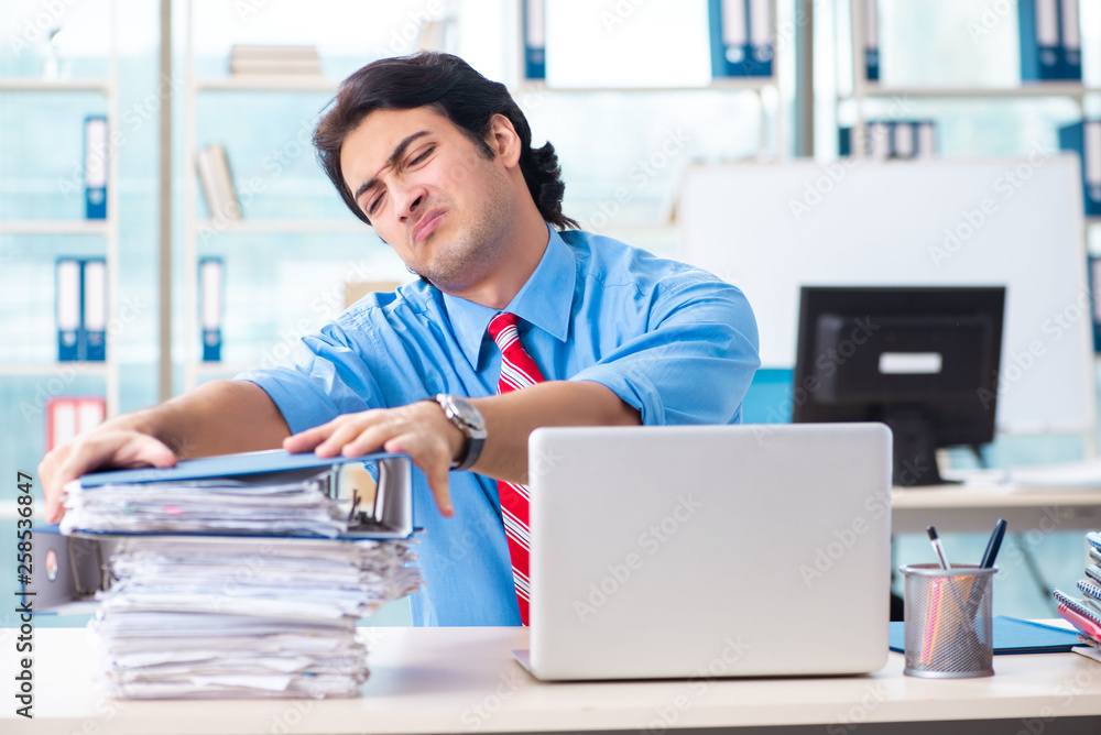 Handsome businessman unhappy with excessive work in the office Handsome businessman unhappy with excessive work in the office