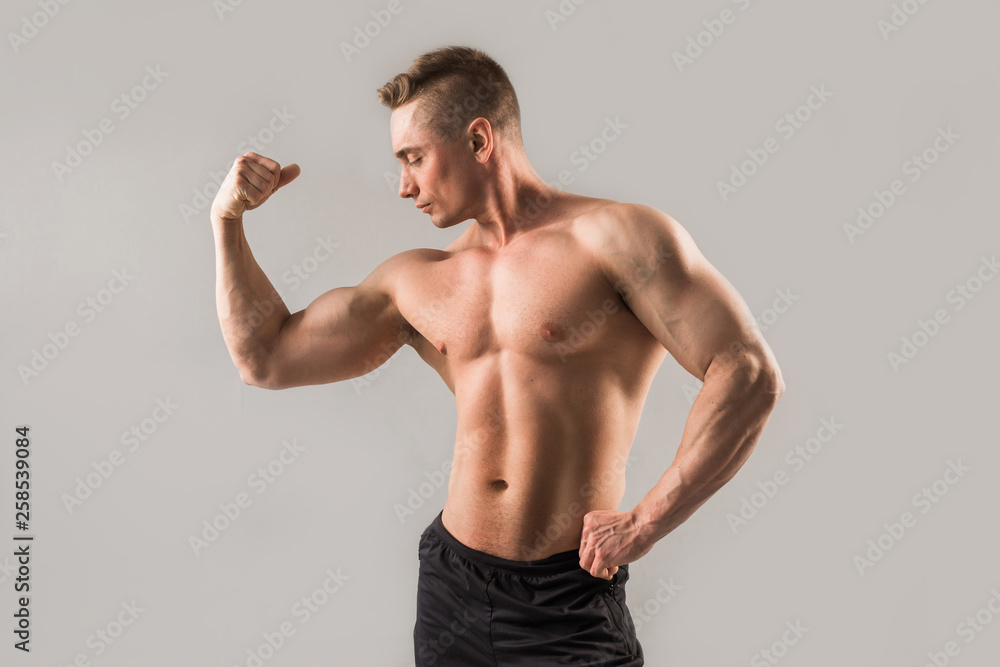 handsome male athlete with pumped muscles on gray background handsome male athlete with pumped muscles on gray background
