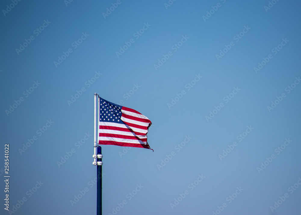 Isolated view of Amerian flag flying against a clear blue sky