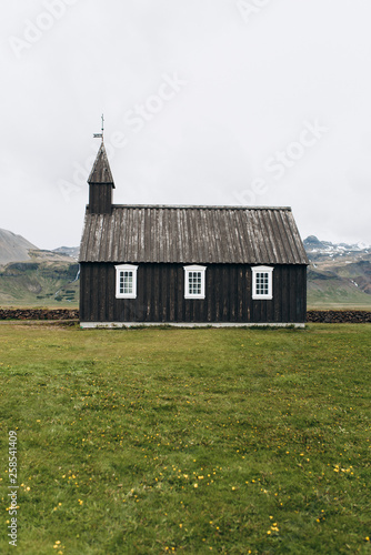 Black wooden church in Iceland against the background of the mountains. Budir Church.