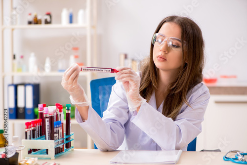 Fototapeta Young beautiful lab assistant testing blood samples 