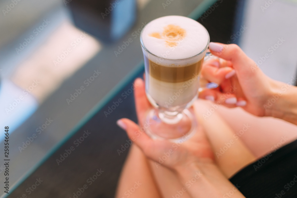 girl holds a cup of cappuccino in a cafe. close up girl holds a cup of cappuccino in a cafe. close up