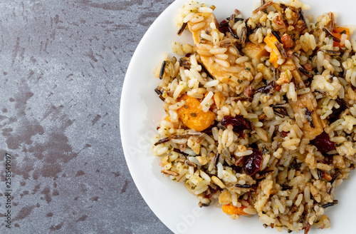 Top close view of chicken with pecans and wild rice on a plate atop a gray background