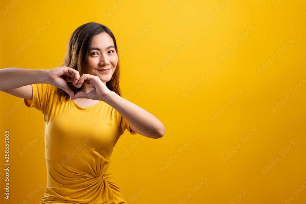 Woman in love showing heart isolated over yellow background Woman in love showing heart isolated over yellow background