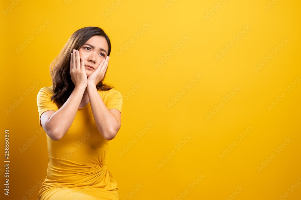 Sad woman isolated over yellow background