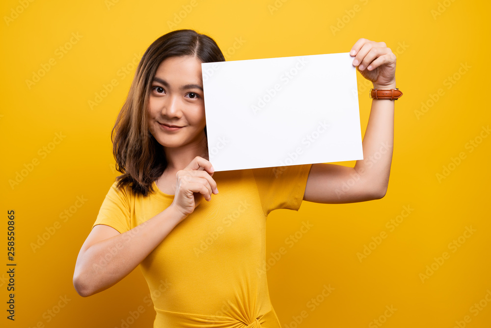 Woman showing paper copy space isolated over yellow background Woman showing paper copy space isolated over yellow background