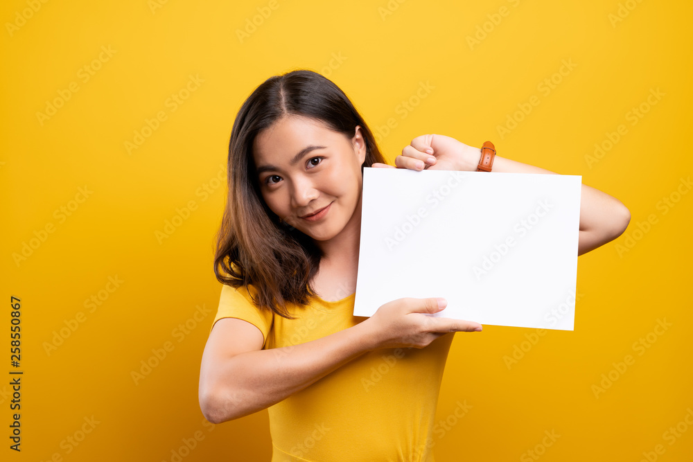 Woman showing paper copy space isolated over yellow background Woman showing paper copy space isolated over yellow background