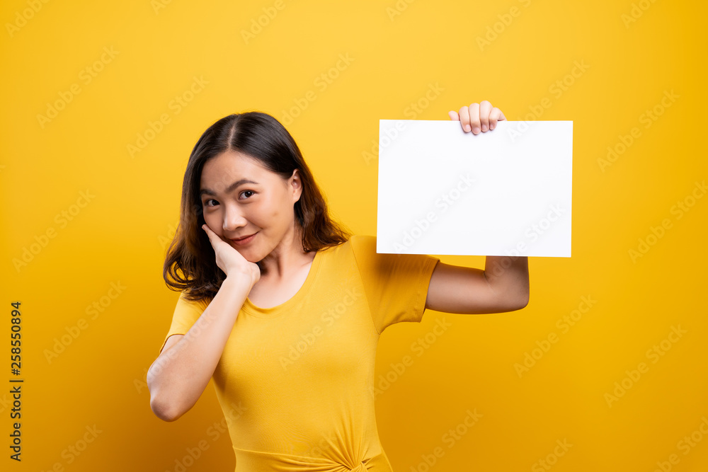 Woman showing paper copy space isolated over yellow background Woman showing paper copy space isolated over yellow background