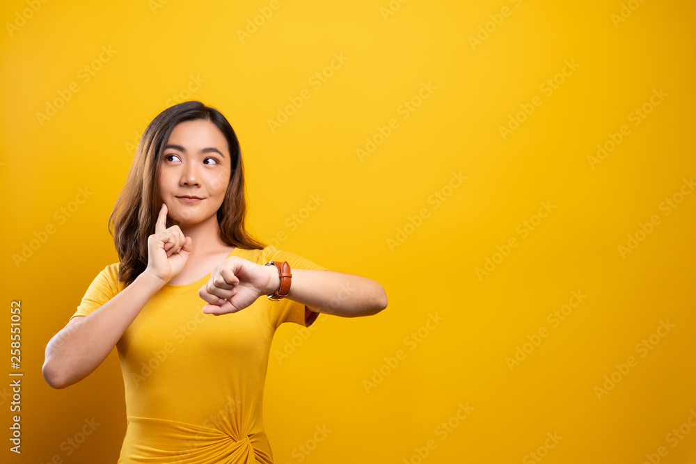 Happy woman holding hand with wrist watch isolated on a yellow background Happy woman holding hand with wrist watch isolated on a yellow background