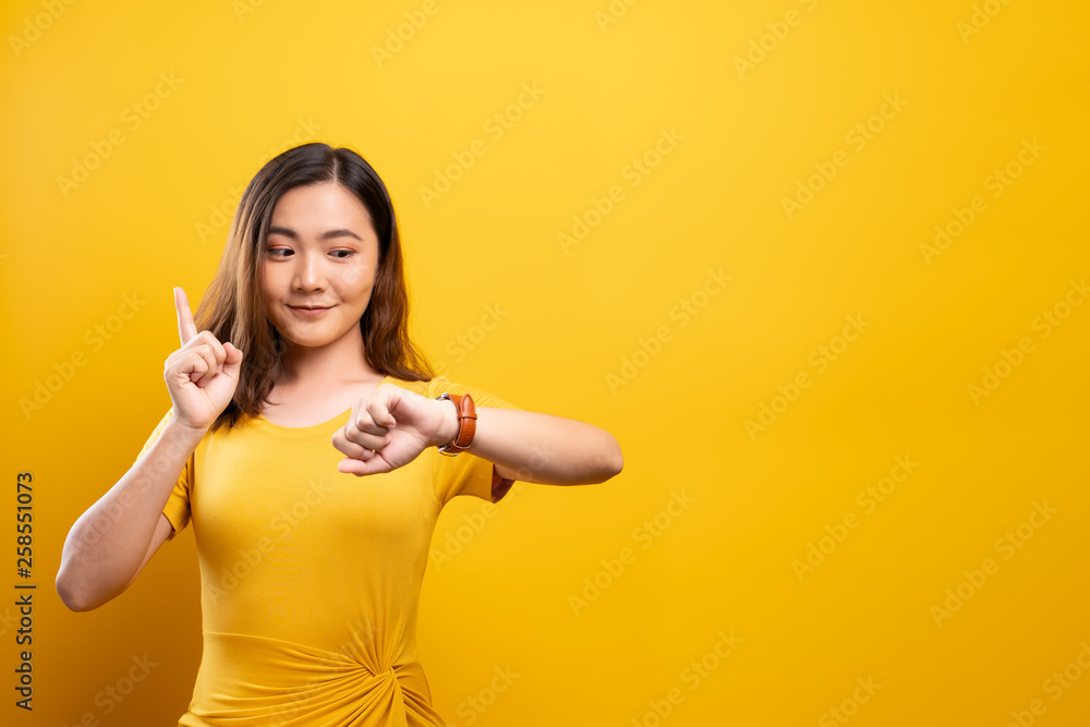 Happy woman holding hand with wrist watch isolated on a yellow background Happy woman holding hand with wrist watch isolated on a yellow background