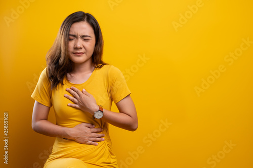 Woman has stomachache isolated over yellow background photo