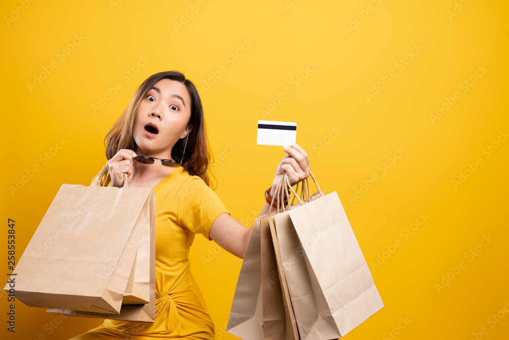 Happy woman holding shopping bags and credit card isolated over background Happy woman holding shopping bags and credit card isolated over background