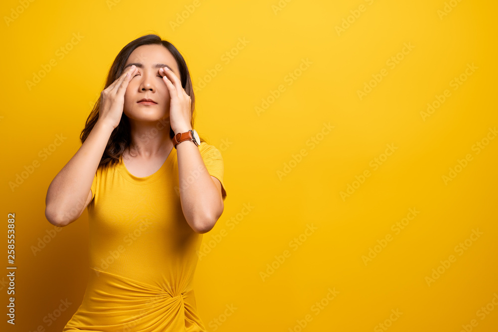 Woman has eyes pain isolated over yellow background Woman has eyes pain isolated over yellow background