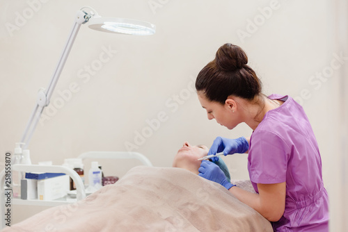 Female young beautician making facial lifting injections