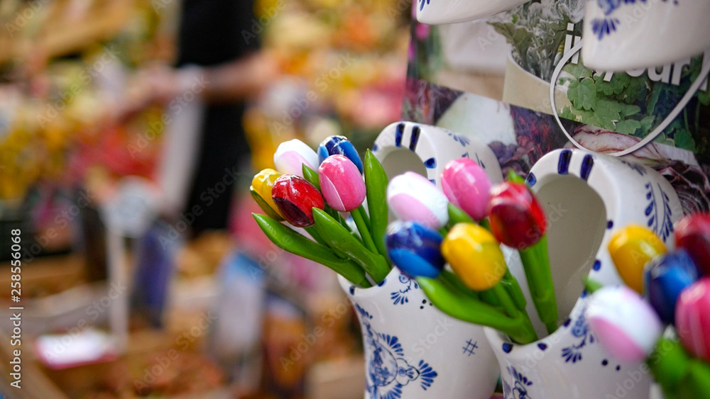 Close up of colorful tulips in tourist shop in Amsterdam centre in Netherlands. Typical dutch shop, small mall in city center, with nice wooden souvenirs, clogs, postcards and magnetic cards. 