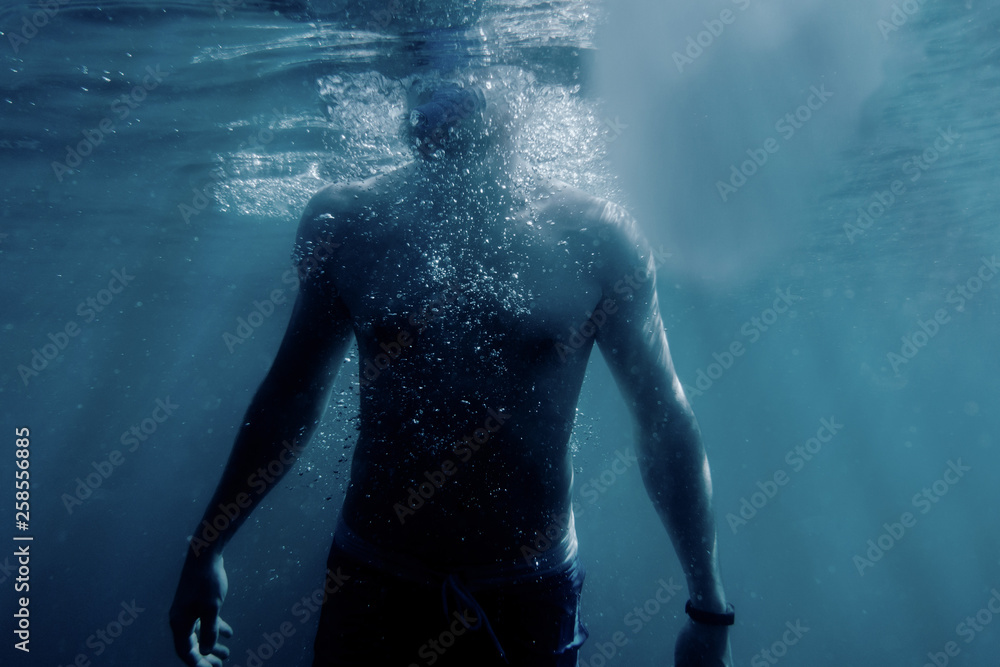Freediver man swimming to the surface of sea.