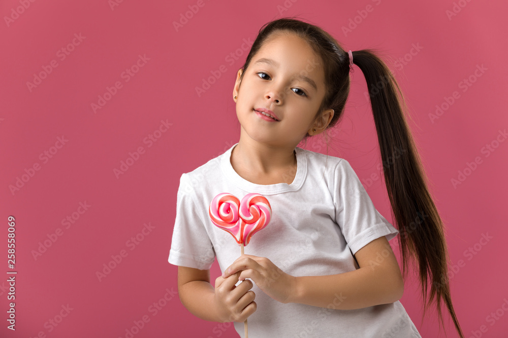 Beautiful cute little child girl with sweet candy lollipop isolated on pink background Beautiful cute little child girl with sweet candy lollipop isolated on pink background