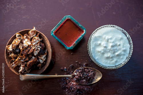 Ingredients of tamarind face pack on wooden surface which are Raw tamarind,raw curd or yogurt and rock salt.Made face pack in blue colored glass bowl.Used to clean bacteria from skin. photo