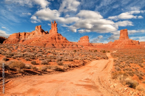 Road leads through Valley of the Gods in central Utah with red rocks and clouds