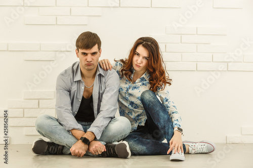 The happy man and woman sit on the background of the white wall