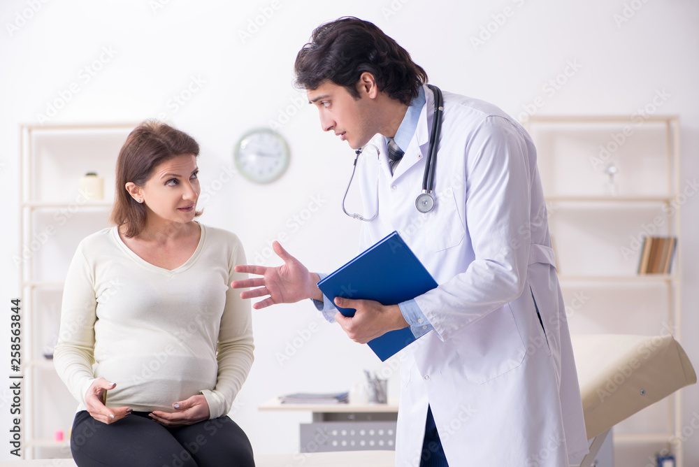 Old pregnant woman visiting young male doctor Old pregnant woman visiting young male doctor
