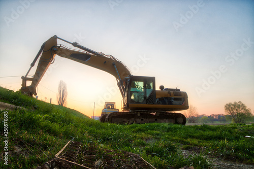 Excavator at sunrise by the river bank