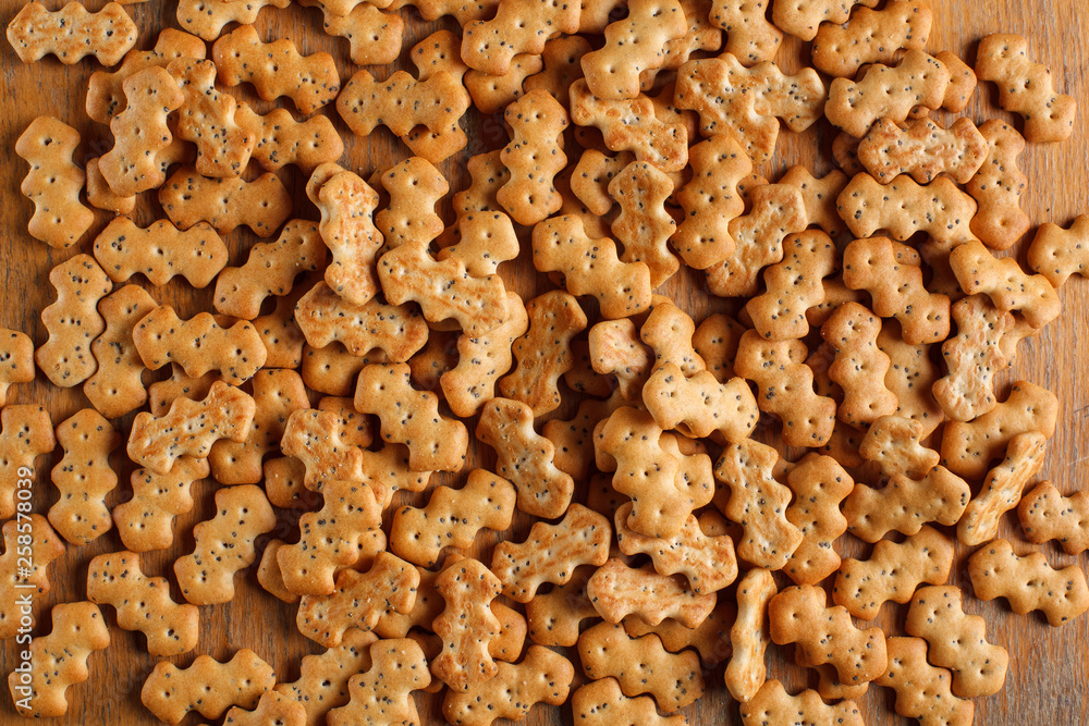 Composition of crackers with poppy seeds, spread out on a wooden background Composition of crackers with poppy seeds, spread out on a wooden background