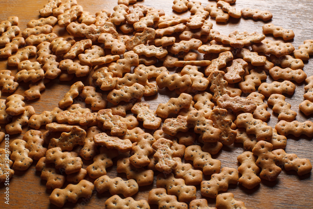 Composition of crackers with poppy seeds, spread out on a wooden background Composition of crackers with poppy seeds, spread out on a wooden background